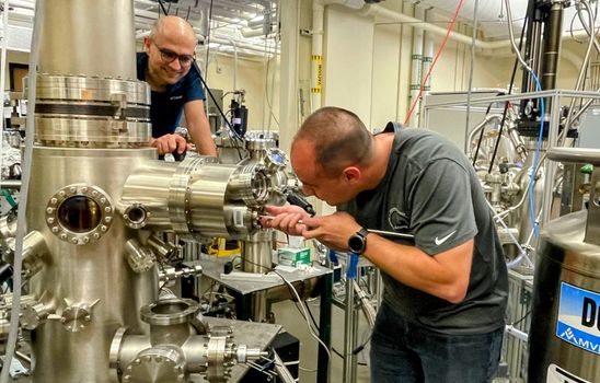 Quantum materials are created one atomic layer at a time in a series of vacuum chambers, as overseen by WVU graduate student Joseph Benigno (left) and postdoctoral research associate Pedram Tavazohi. (WVU Photo)
